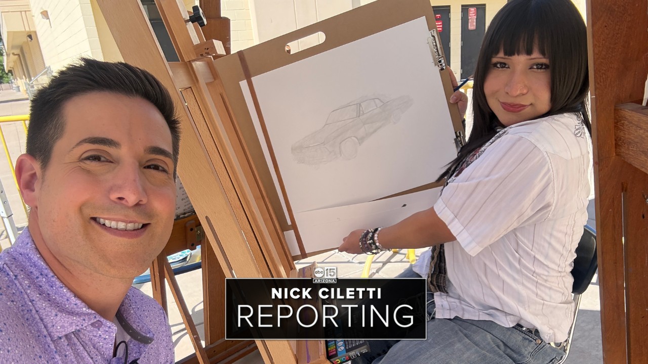 Young Valley Artists Rev Up Creativity with Classic Car Canvas Challenge Man taking a selfie beside a woman drawing a classic car on a large sketch pad at an easel, with on-screen text reading “NICK CILETTI REPORTING” and “Young Valley Artists Rev Up Creativity with Classic Car Canvas Challenge”