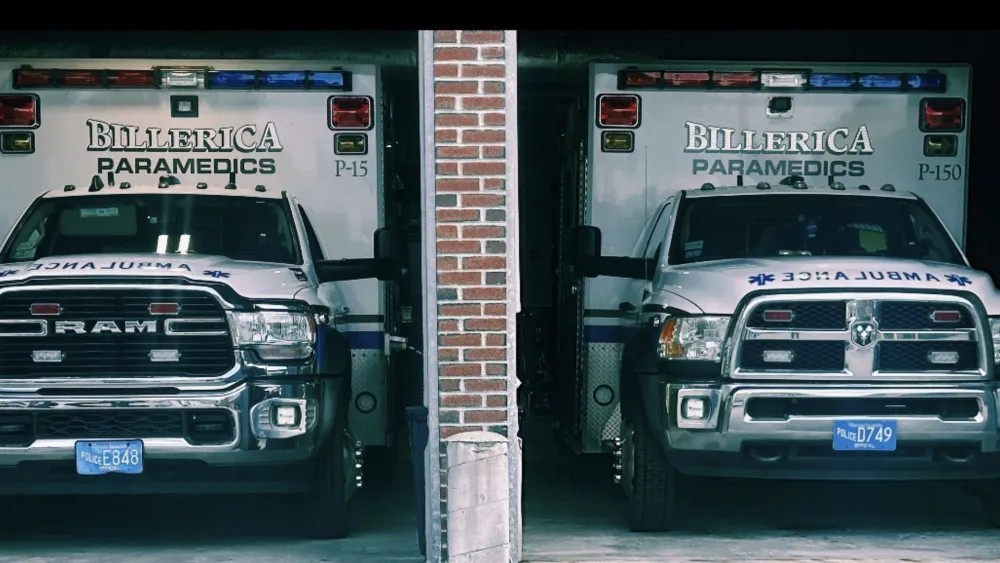 Heroic Massachusetts Paramedics Save 6 Lives in Dramatic House Fire Rescue Two Billerica Paramedics ambulances parked side by side in garage bays, separated by a brick column, with blue police license plates visible.