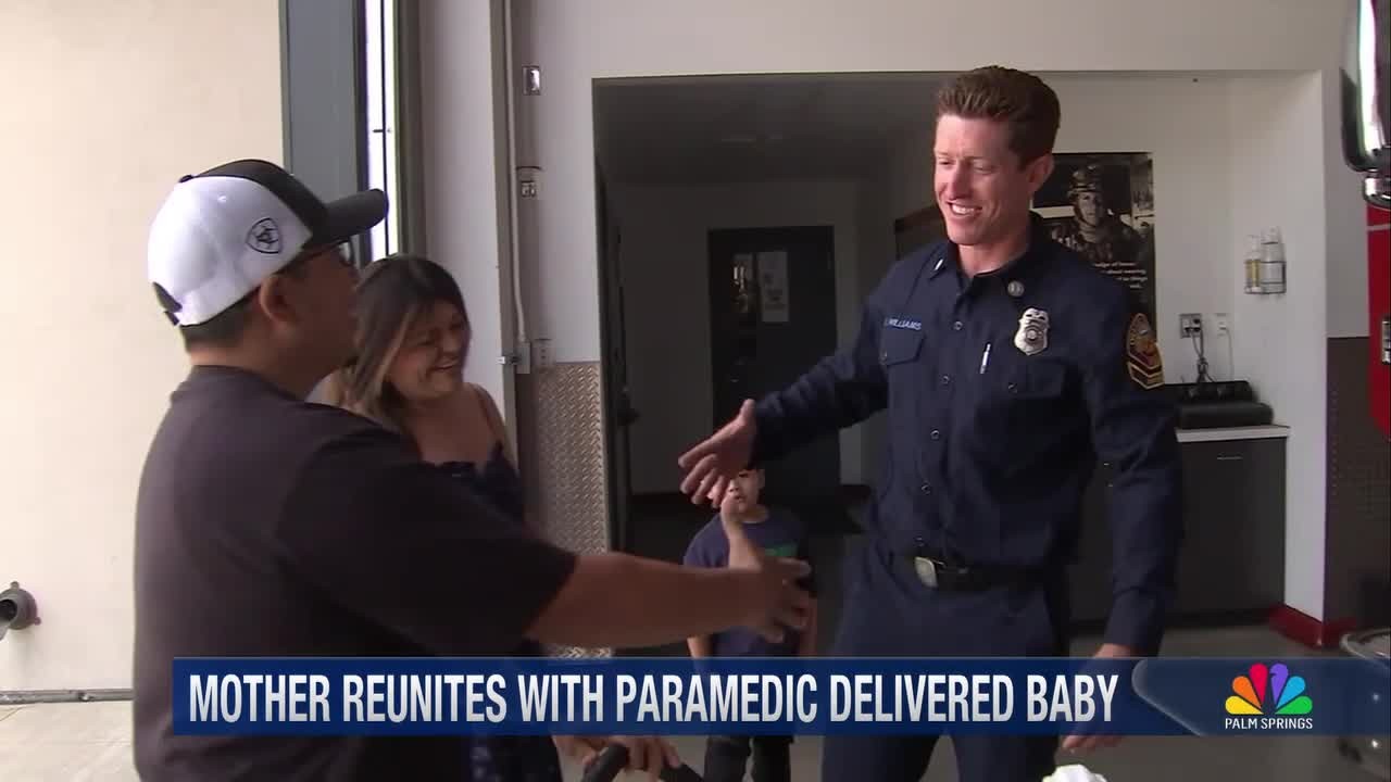 Firefighter or paramedic in uniform reaches out to greet a couple and child inside a station, with on-screen text reading “MOTHER REUNITES WITH PARAMEDIC DELIVERED BABY” and an NBC Palm Springs logo.