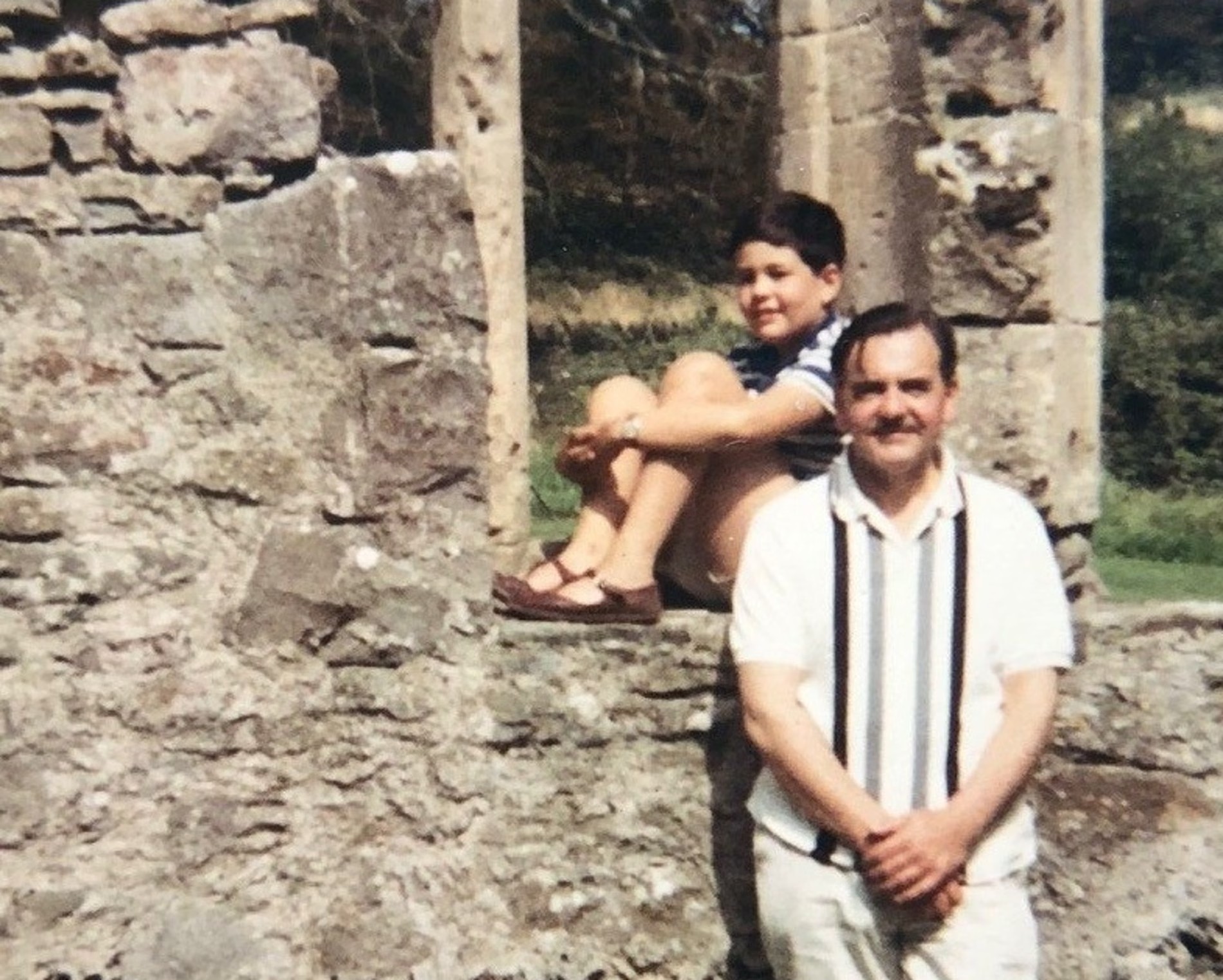 TEST TEST TEST TEST TEST Man and child posing by old stone ruins, with the child sitting on a ledge and the man standing in front; text at bottom reads “TEST TEST TEST TEST TEST”